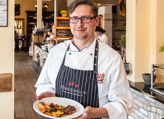 Oliver Firla serviert Fleischgericht in Odins Gasthaus in Haddeby